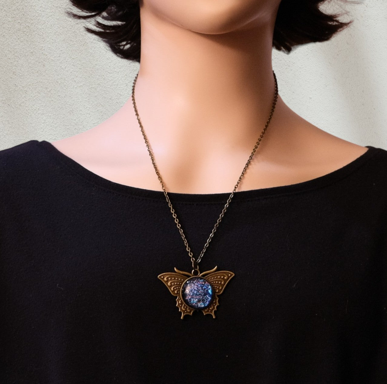 Butterfly necklace with a blue gemstone pendant on a black shirt