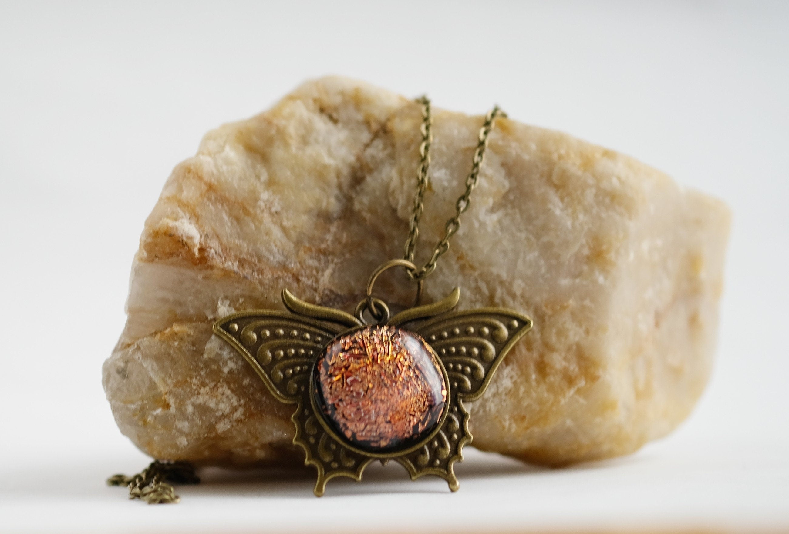 Butterfly pendant necklace, antiqued brass tone with orange dichroic fused glass center stone on a 20 inch antiqued brass chain seeds glassworks seedsglassworks