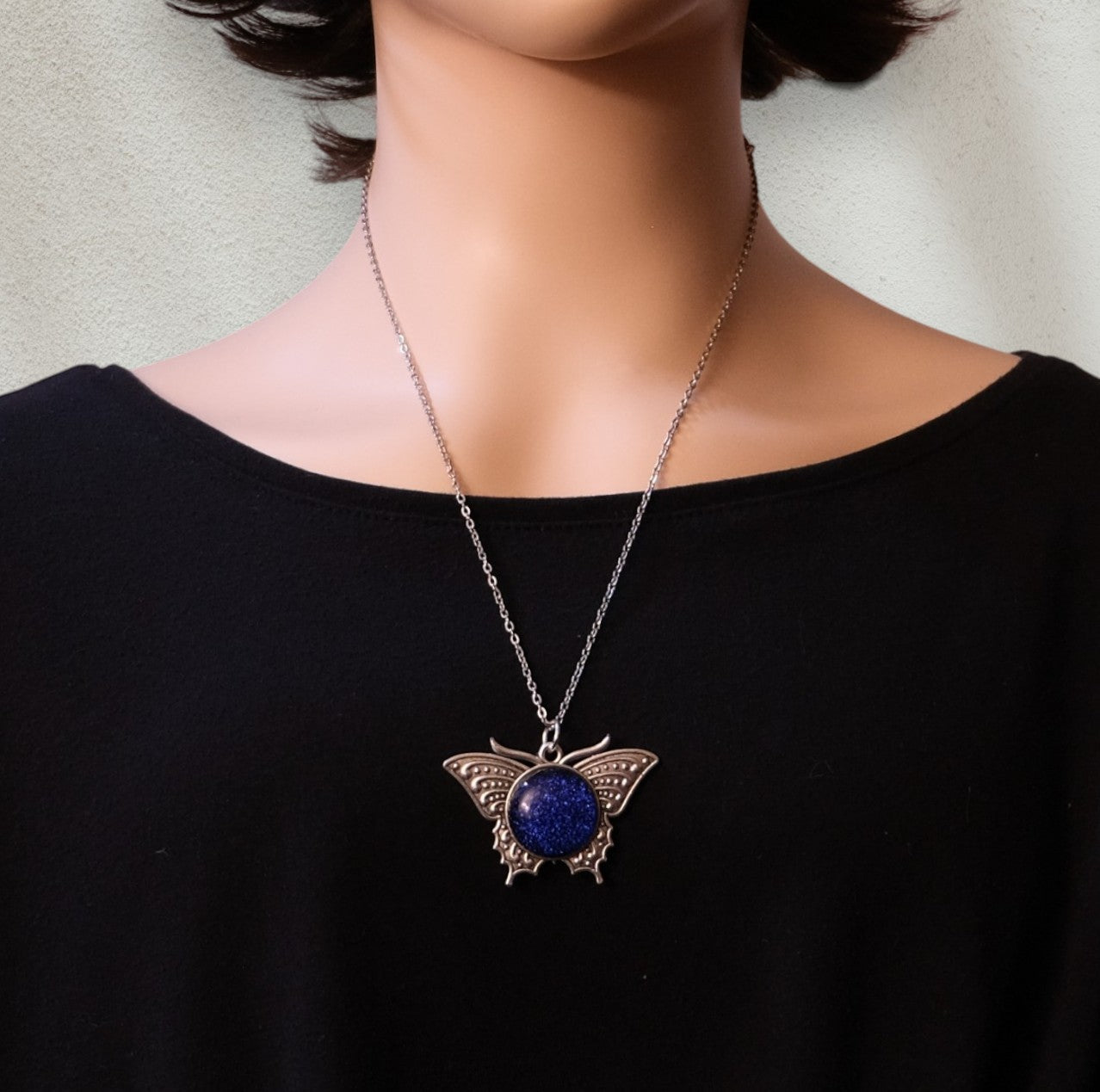 Butterfly pendant necklace with blue stone on a black shirt