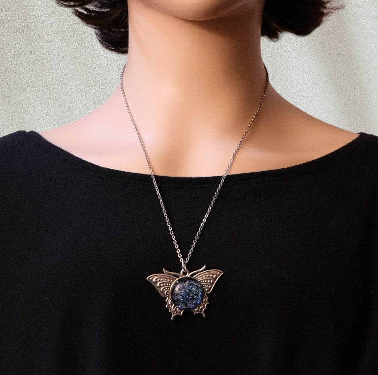 Butterfly necklace with a blue pendant on a black shirt