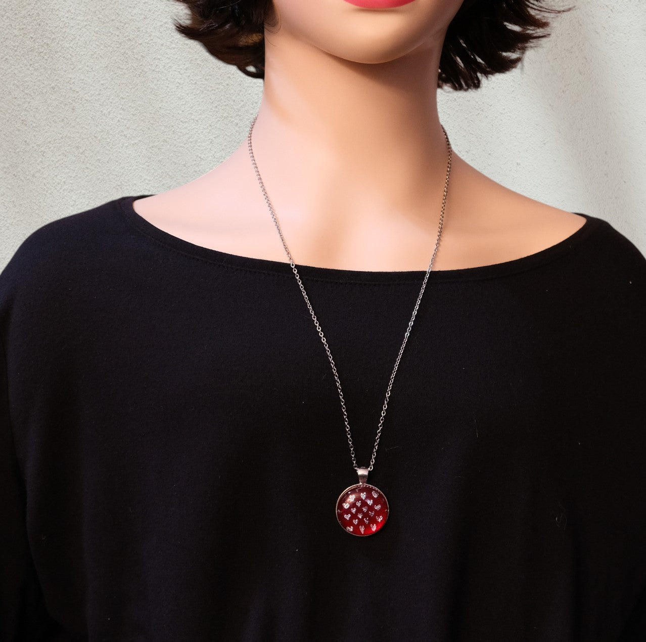 Necklace with a red pendant worn by a person against a neutral background