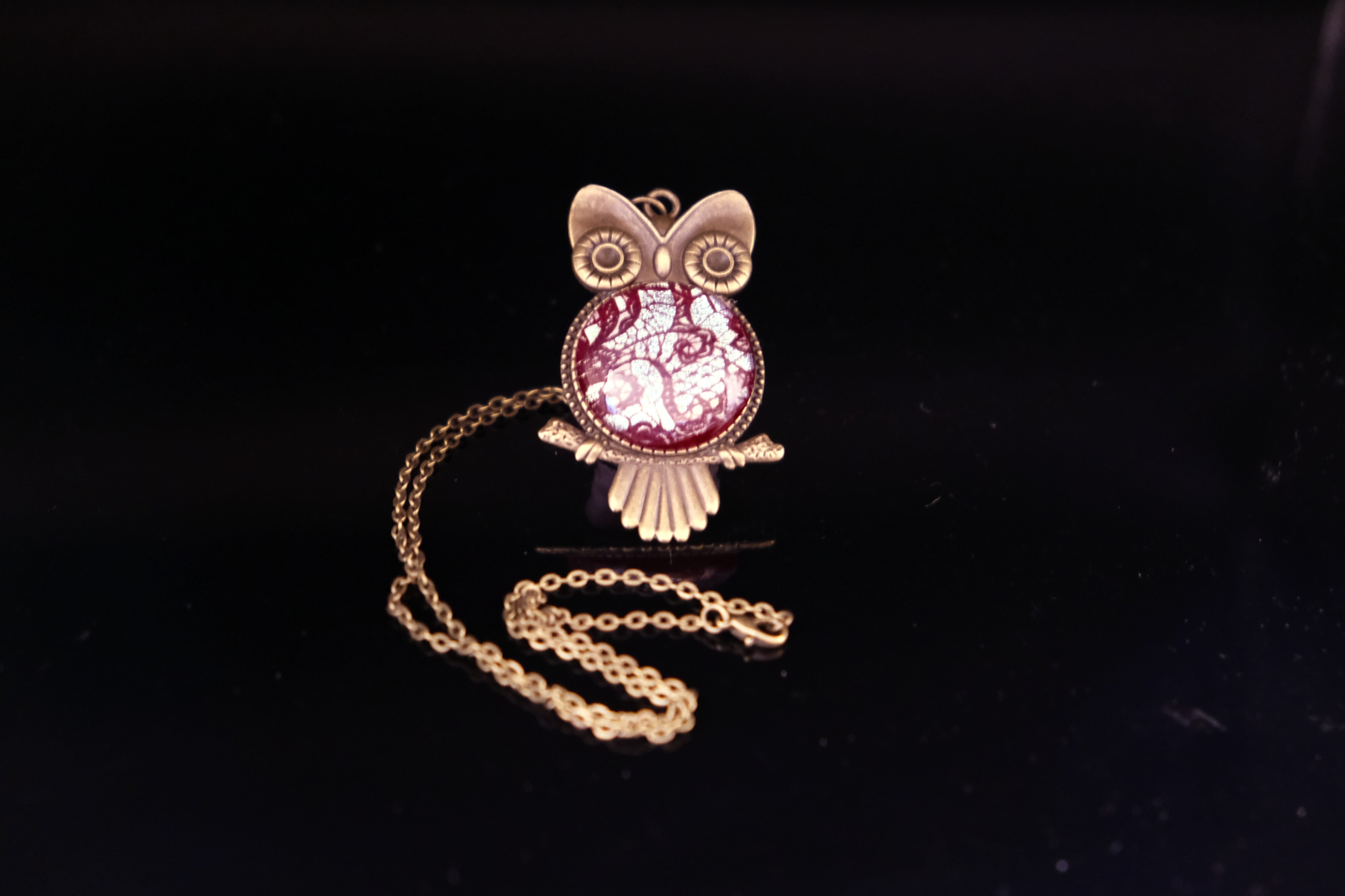 Owl-shaped pendant with chain on a black background