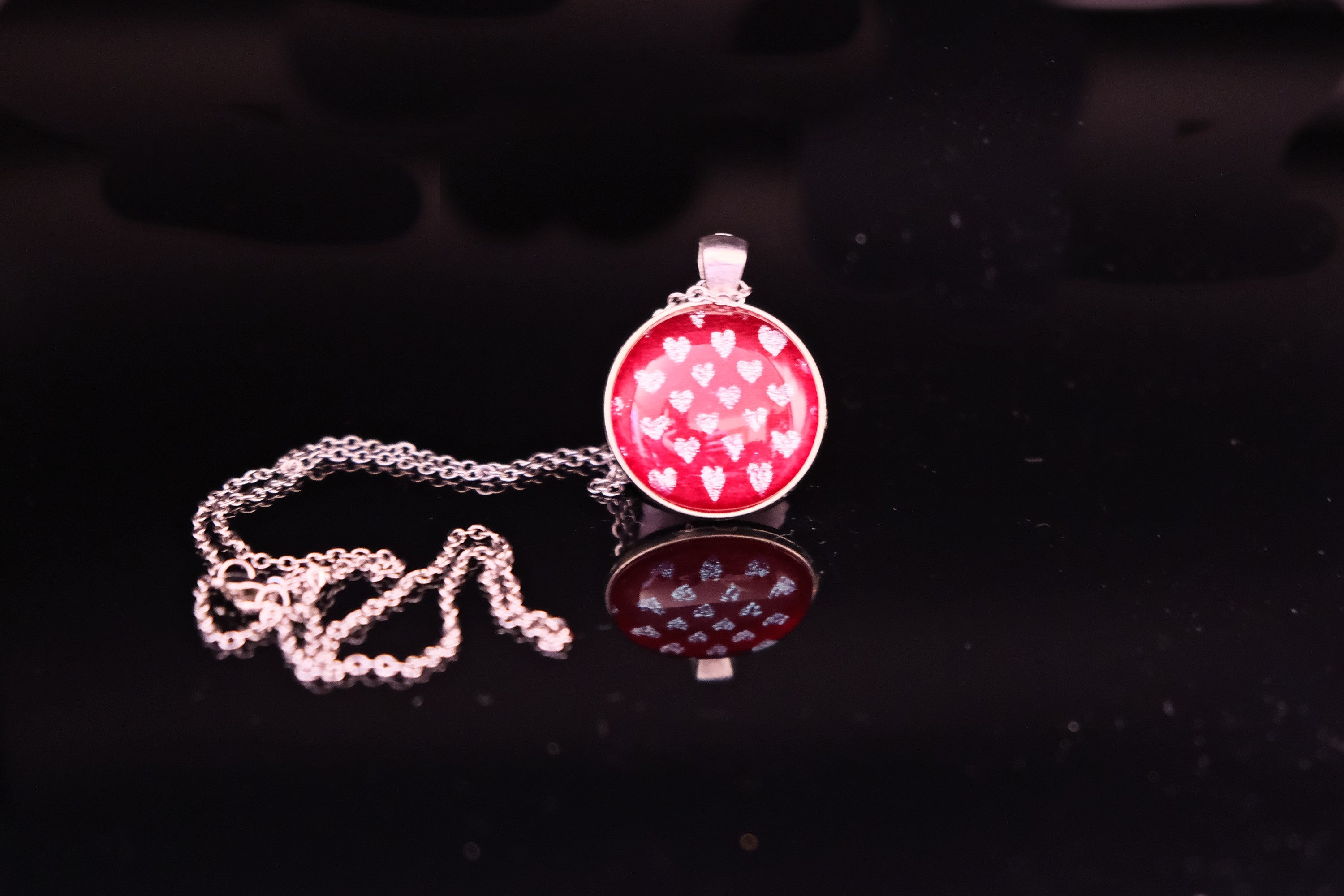 Necklace with a red pendant featuring white hearts on a black background