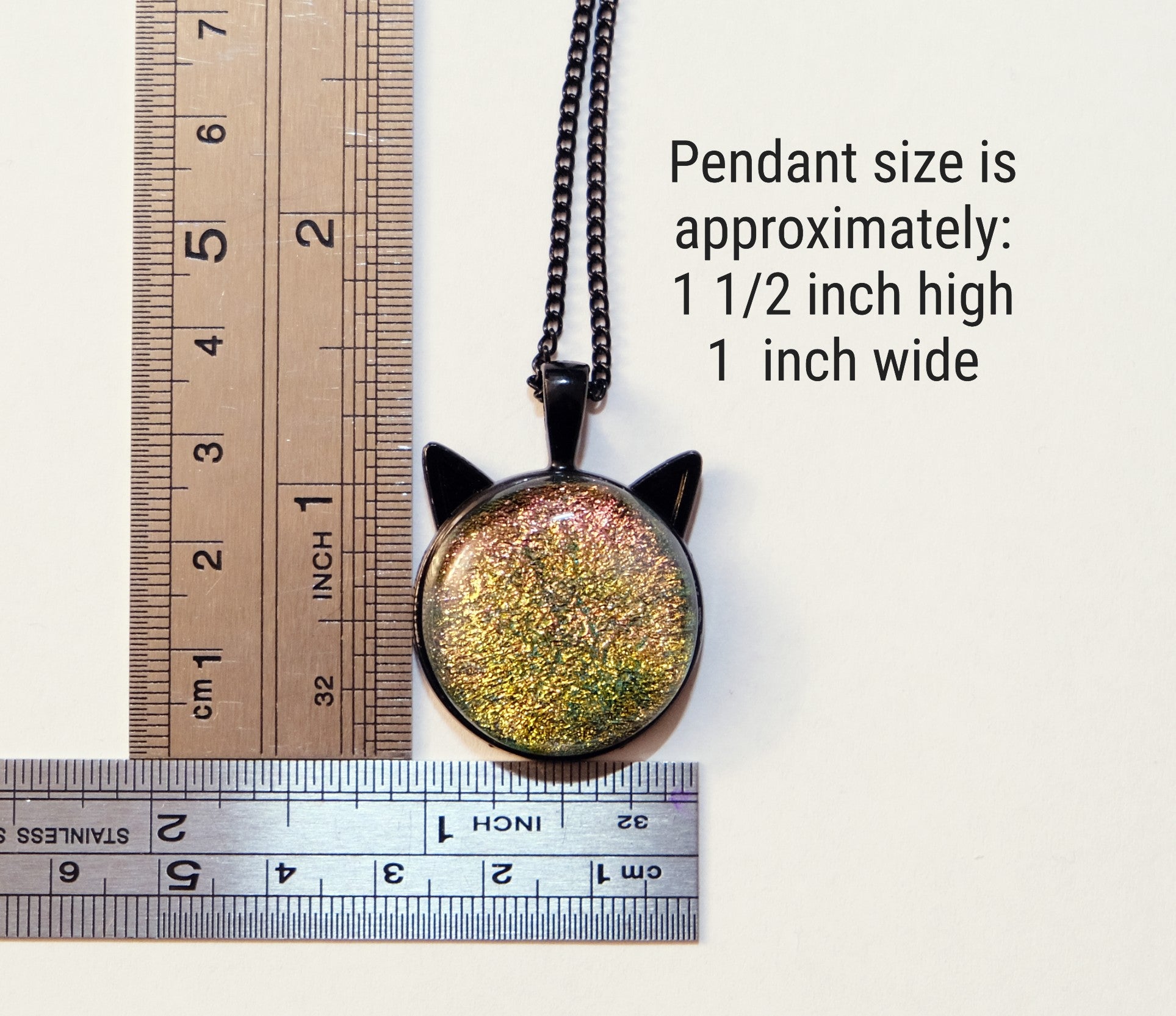 Cat-shaped pendant with a ruler for size reference on a white background
