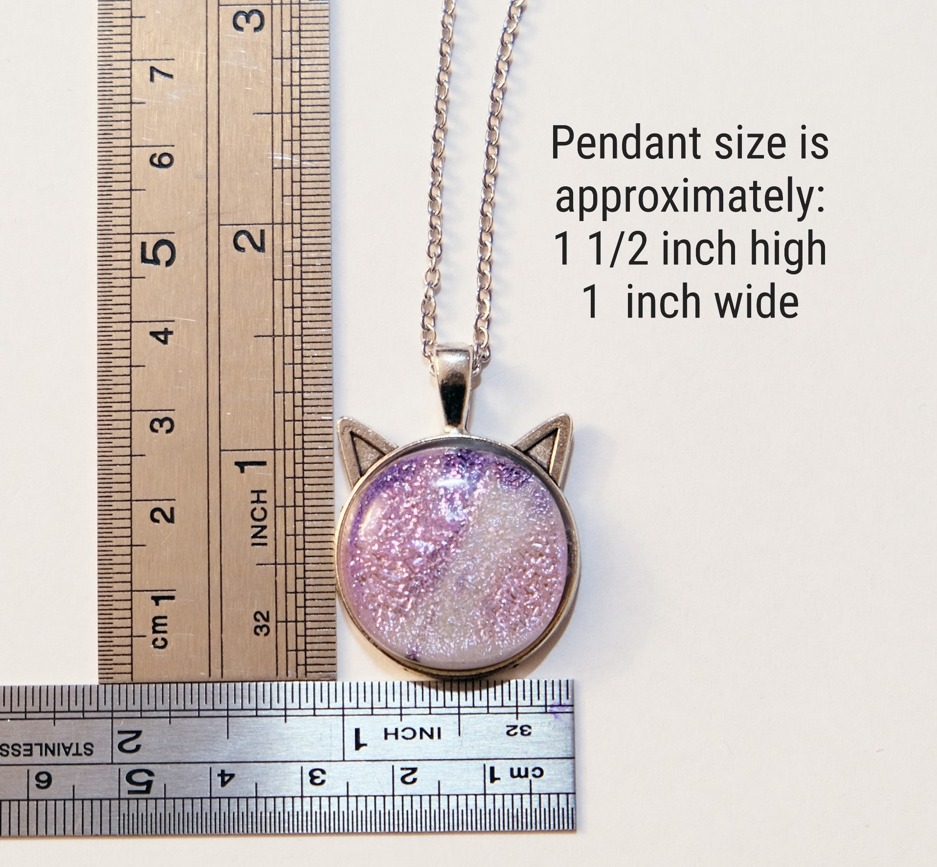 Cat-shaped pendant with glittery pink and purple design, shown with a ruler for size reference.