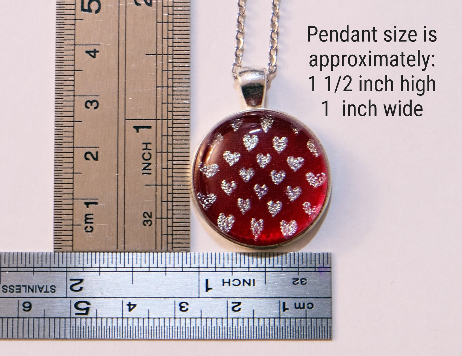 Pendant with heart pattern on a chain, shown with two rulers for size reference.