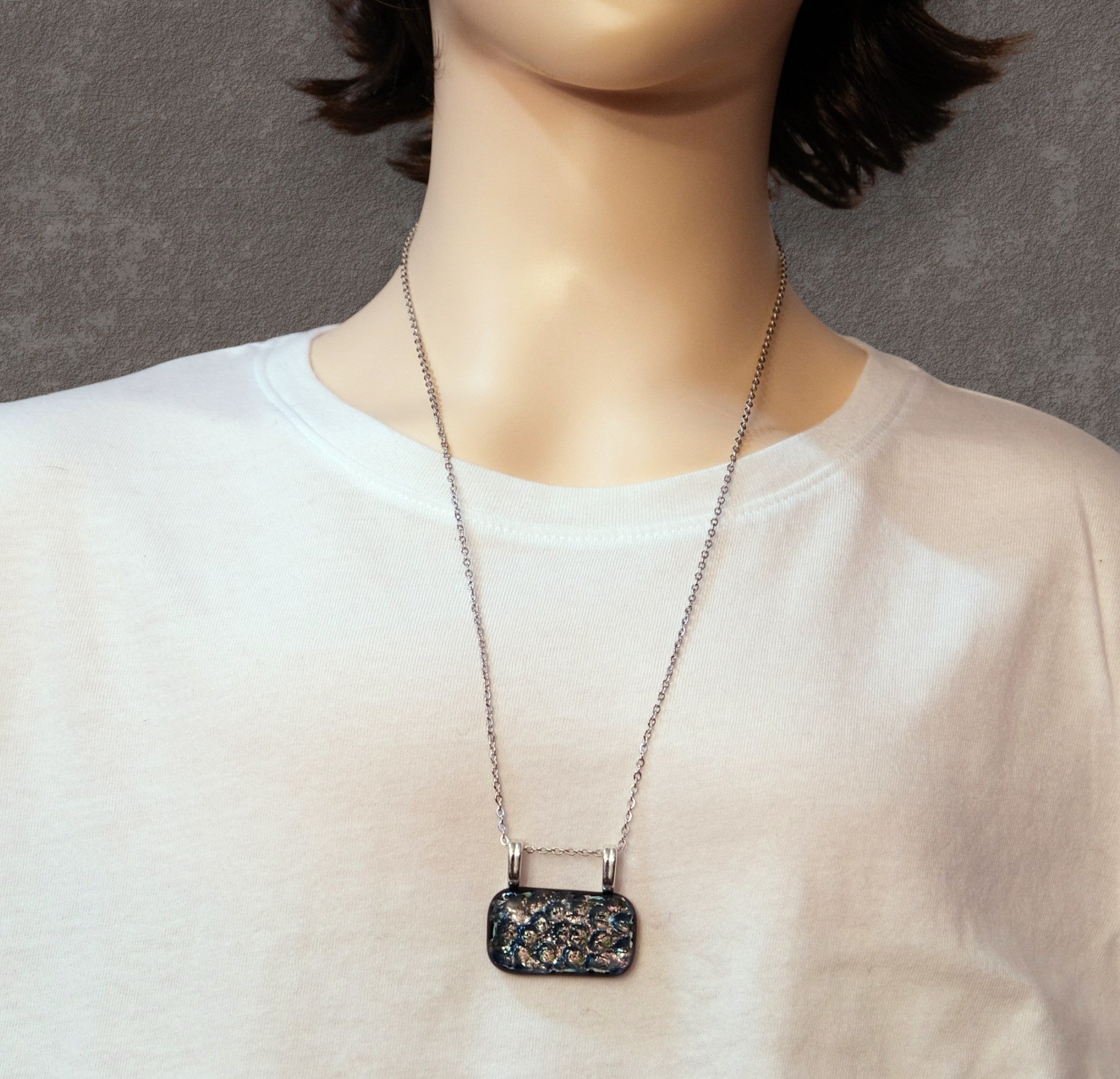 Necklace with a pendant on a mannequin wearing a white shirt against a gray background