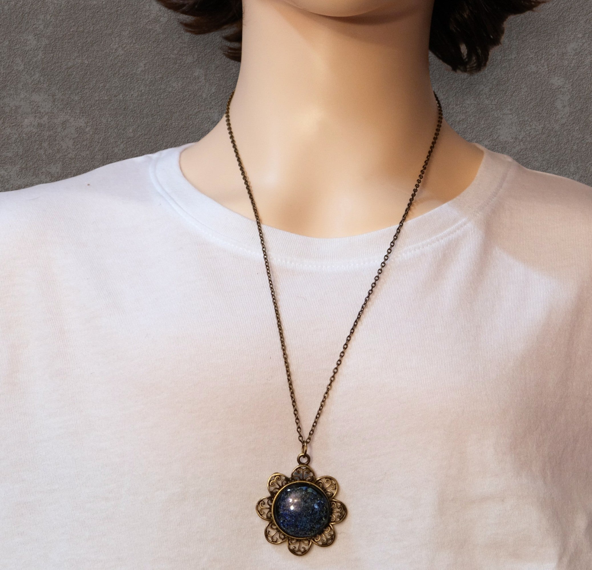 Necklace with a decorative pendant worn by a person on a plain background