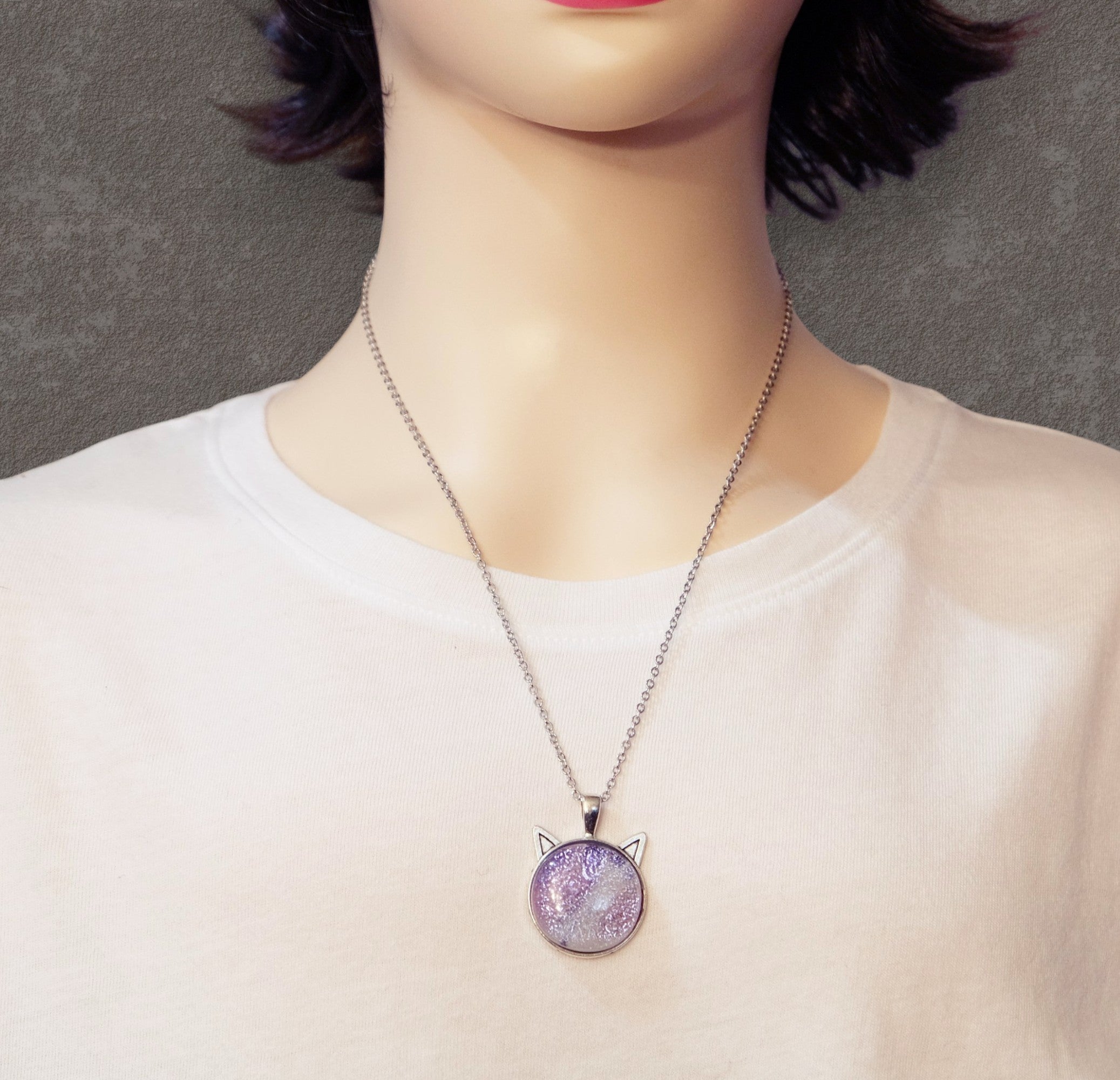 Necklace with a purple pendant on a mannequin wearing a white shirt.