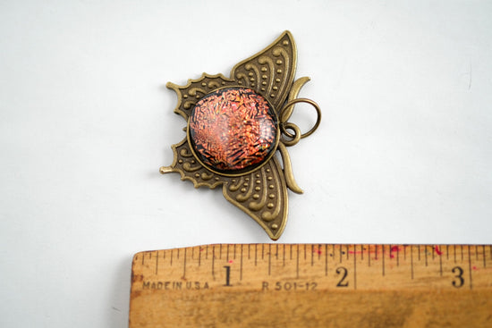 Butterfly pendant necklace, antiqued brass tone with orange dichroic fused glass center stone on a 20 inch antiqued brass chain seeds glassworks seedsglassworks
