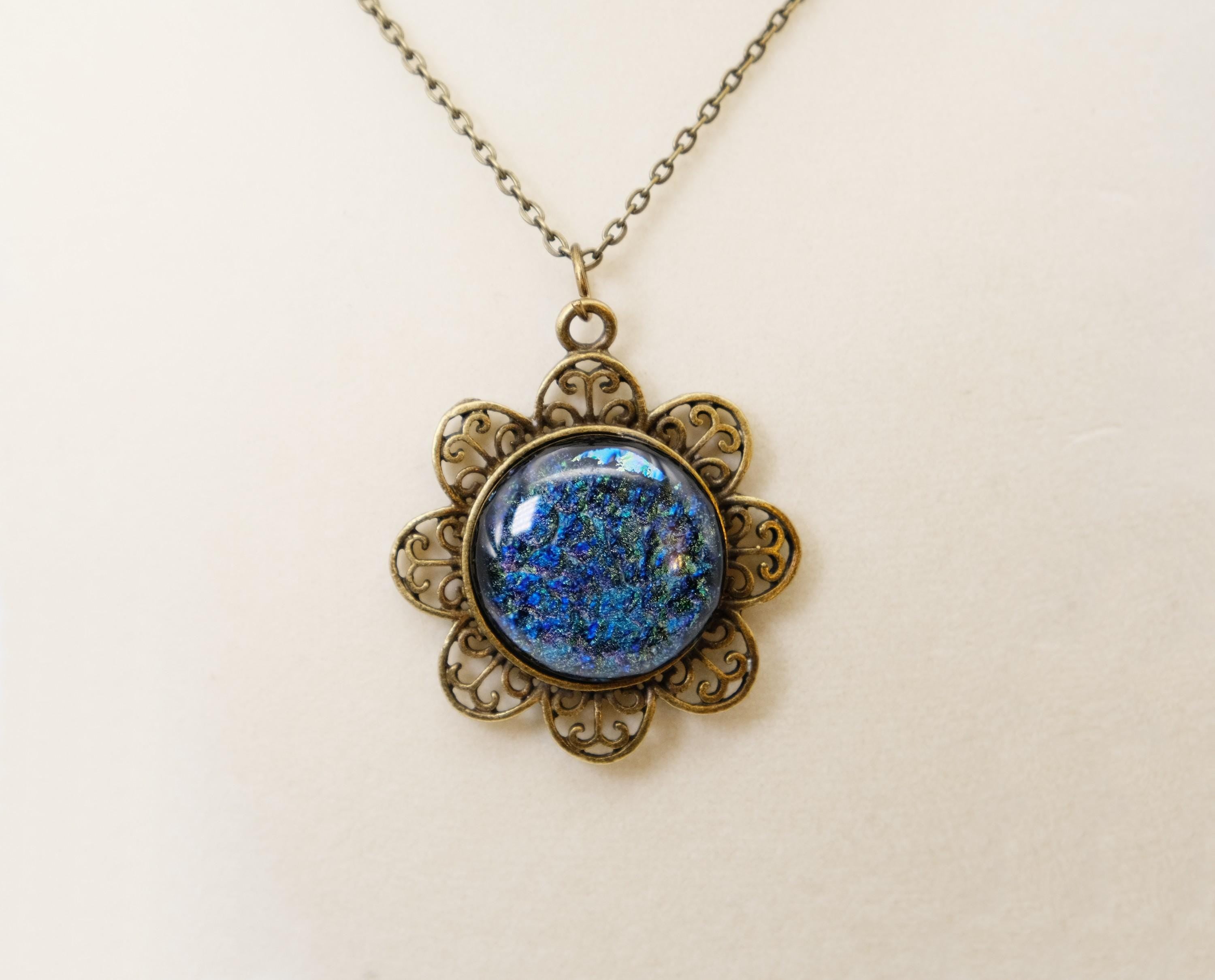 Antiqued Brass Flowered pendant necklace with Fused Glass multicolor/blue Dichroic cabochon on 24 inch antiqued brass chain jewelry. seeds glassworks seedsglassworks