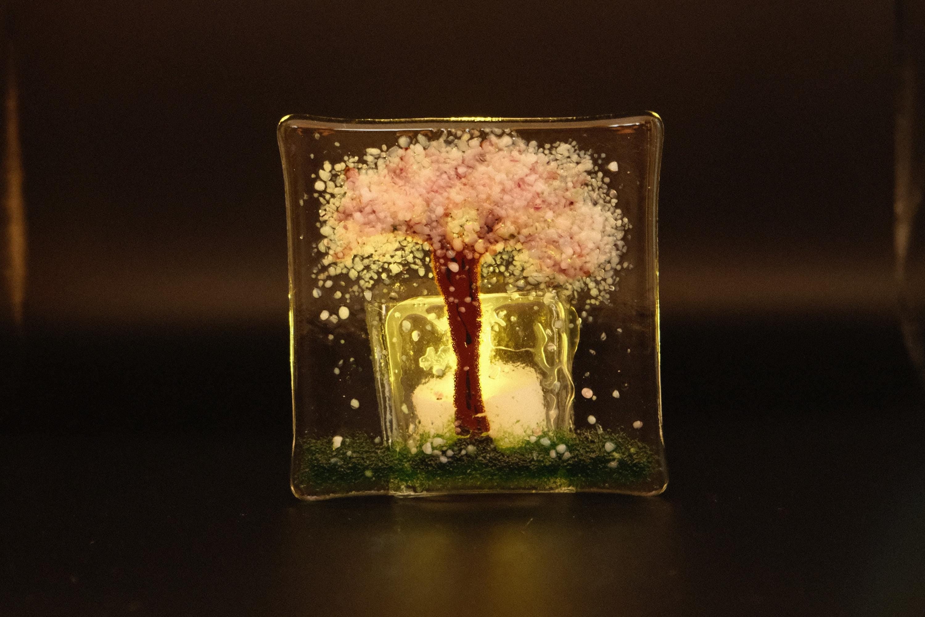 Decorative glass piece with a tree design on a dark background
