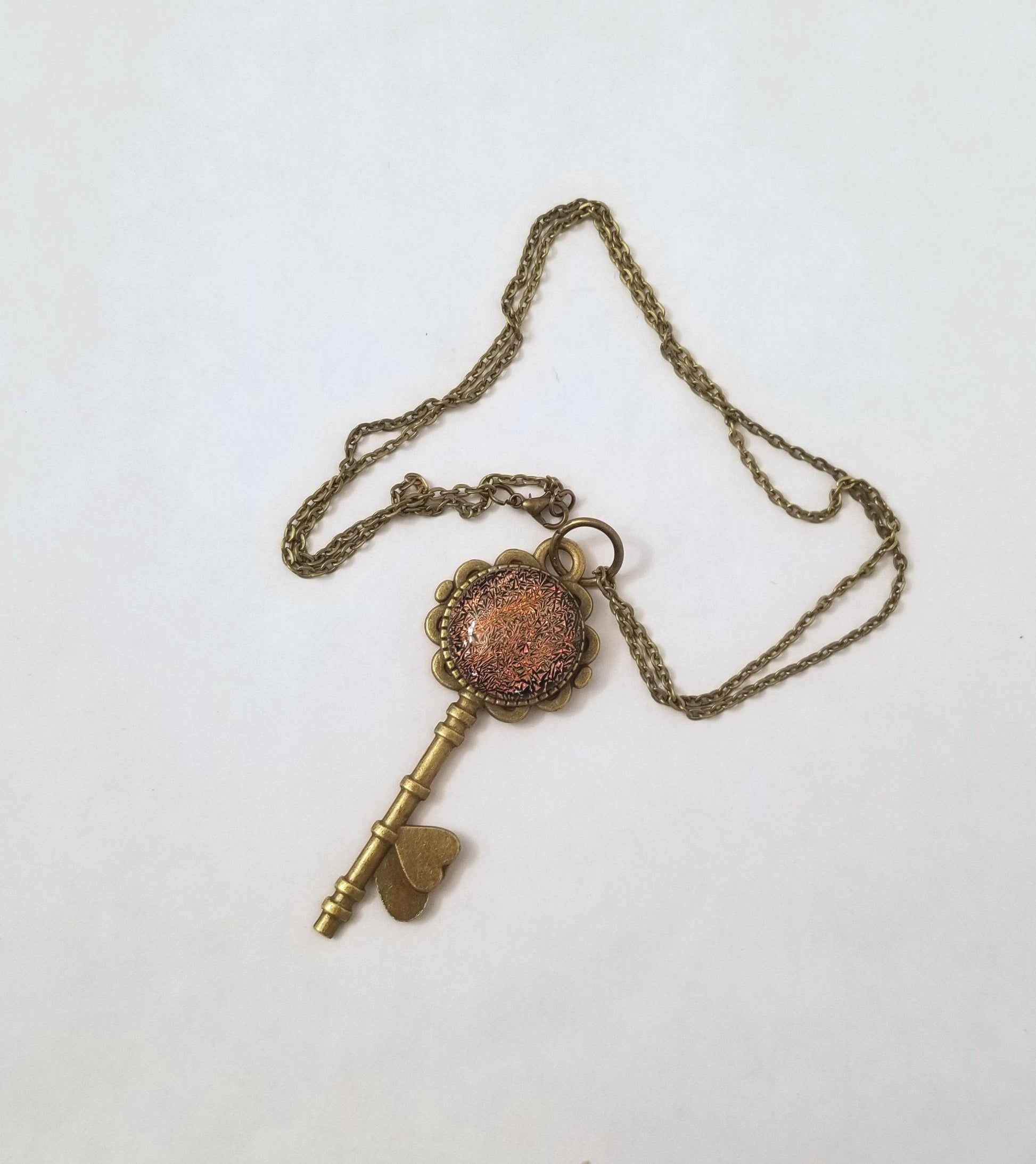Antiqued Brass  Flowered Skeleton Key with Fused Glass Orange Dichroic cabochon on 24 inch brass plated chain. seeds glassworks. seedsglassworks