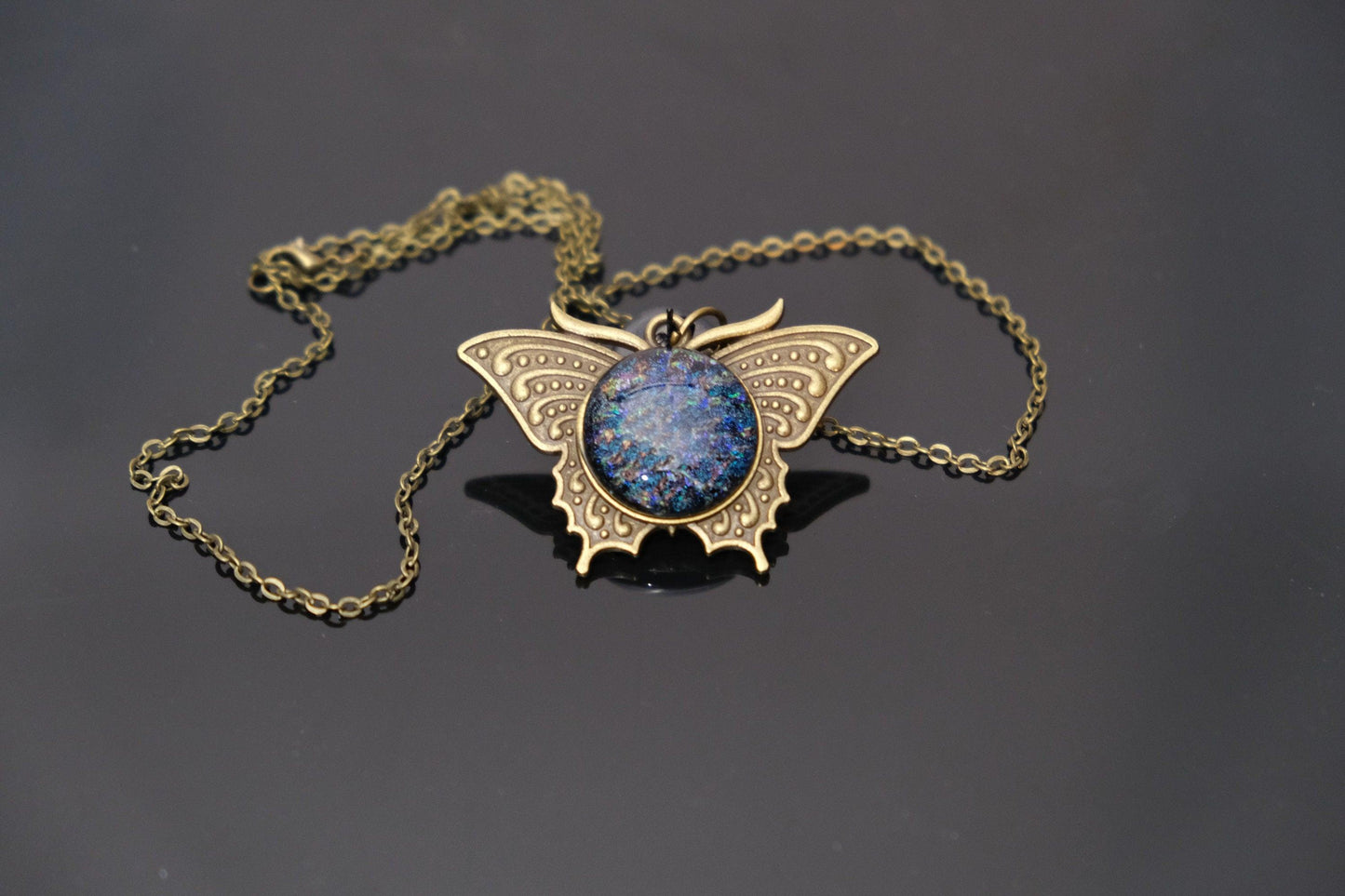 Butterfly pendant necklace, brass tone with blue/multicolor dichroic fused glass center stone on a 20 inch brass toned chain seeds glassworks seedsglassworks